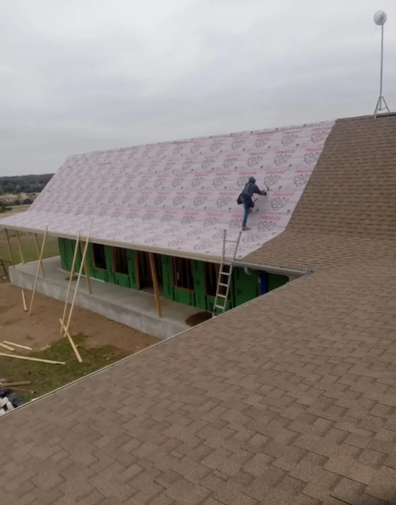 Worker preparing underlayment for a metal roof installation in Superior